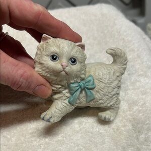 A vintage Homco ceramic figurine of a white Persian kitten with a blue bow.